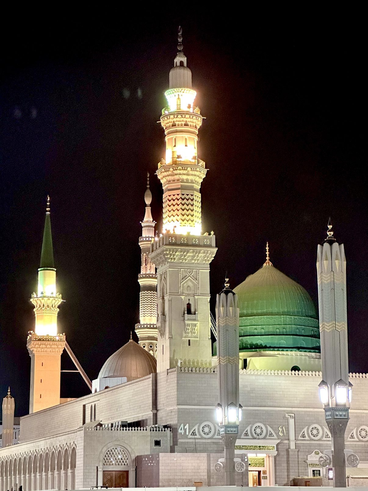 The Prophet's Mosque in Madinah at night, the Green Dome and minarets glowing
