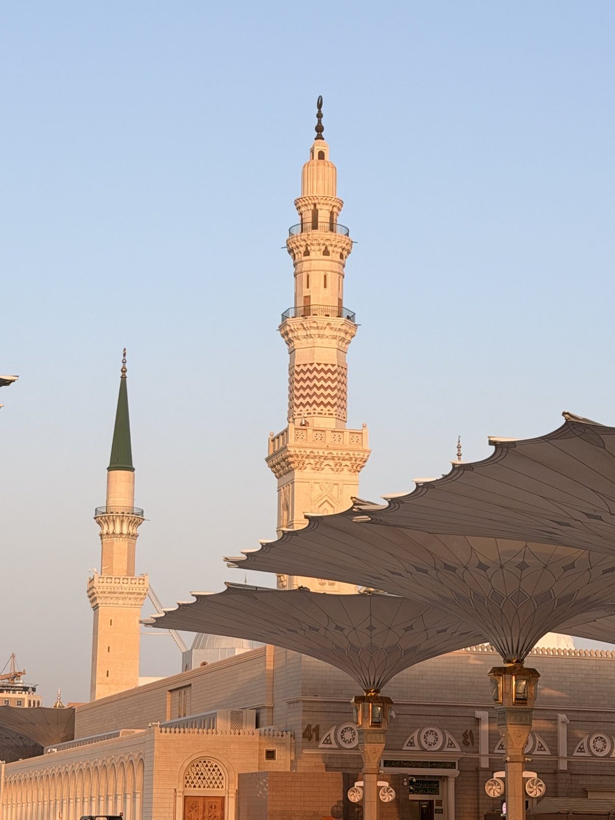 A minaret and courtyard umbrella of the Prophet's Mosque at dusk