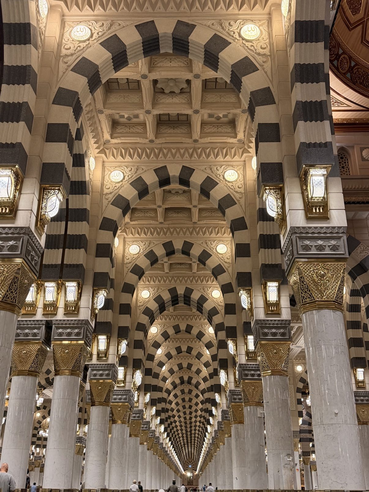 The colonnades of the Prophet's Mosque, arches and chandeliers receding into the distance
