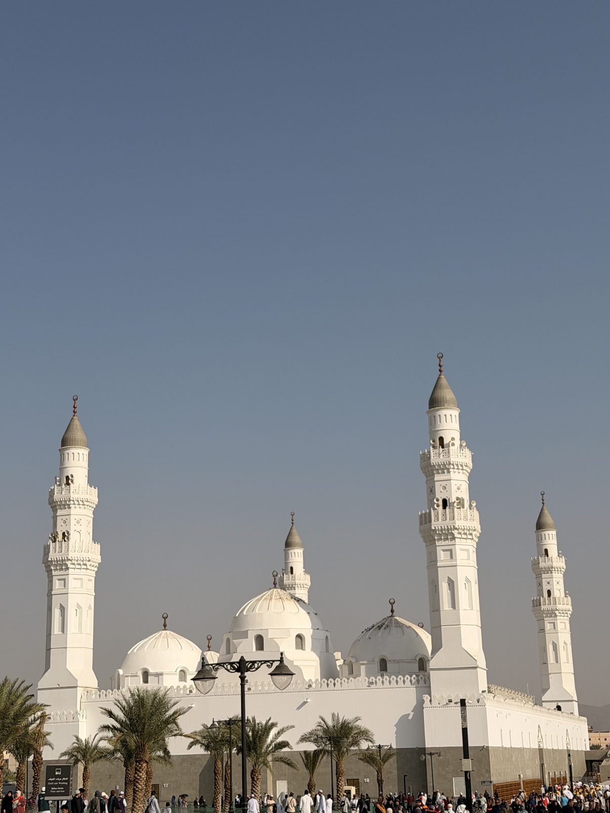 A white mosque with four slender minarets under a clear sky