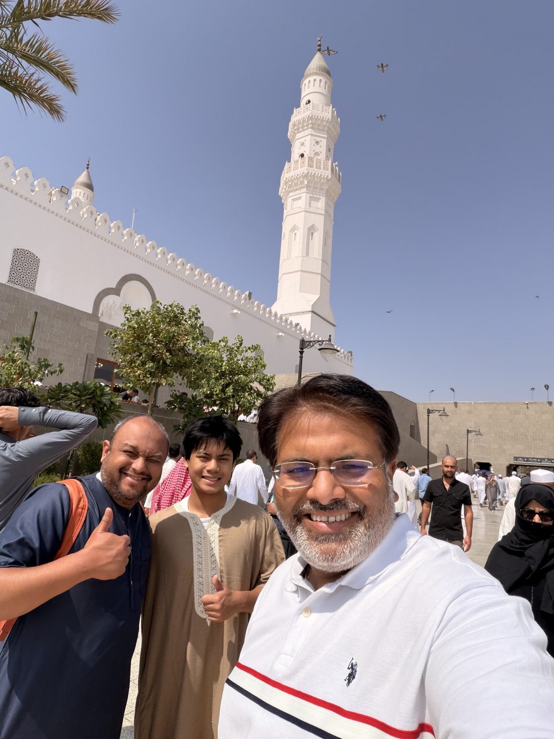 Group members smiling outside Masjid Quba beneath its white minaret