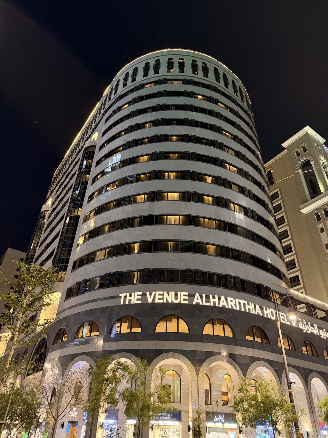 The curved facade of the Venue Al Harithia hotel in Madinah lit up at night
