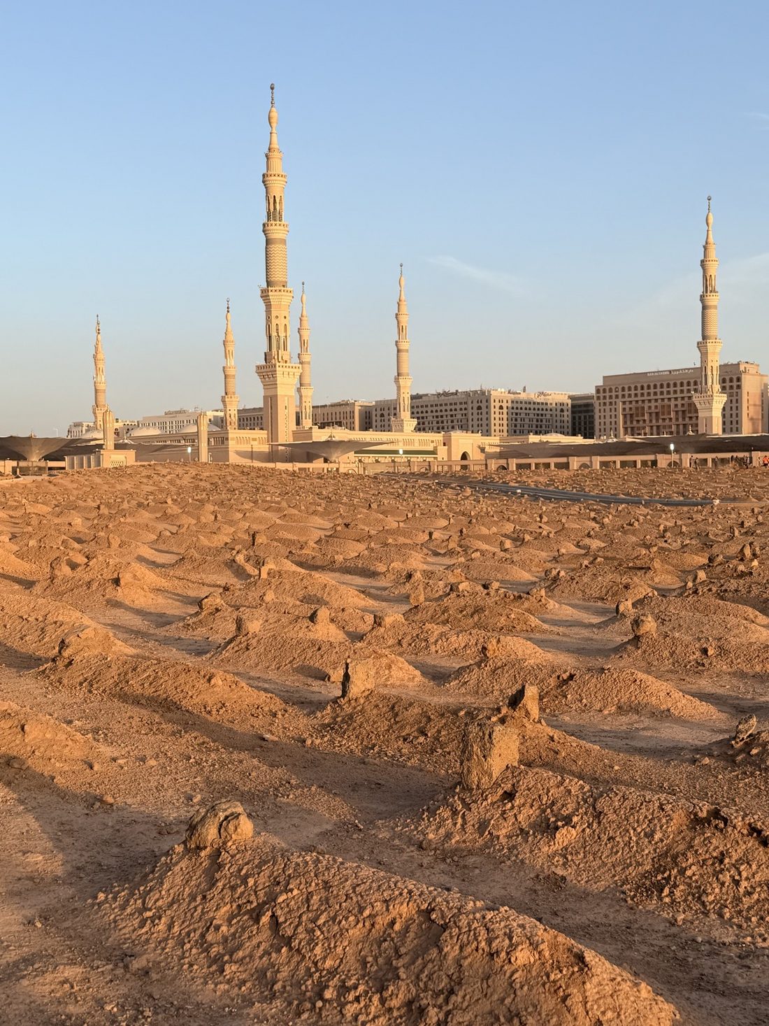 Jannat al-Baqi in golden light with the minarets of the Prophet's Mosque behind it
